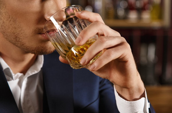 Closeup of a man drinking whiskey