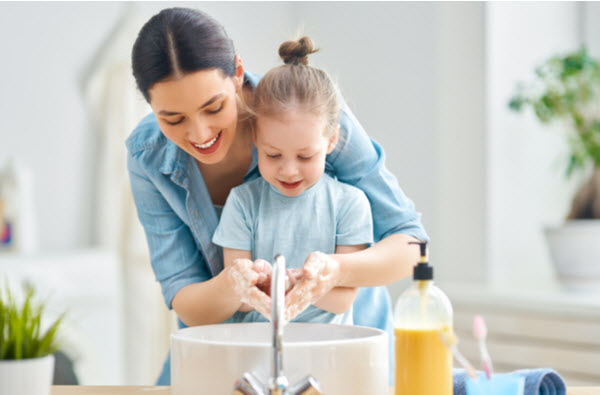 Mother and daughter happily washing hands